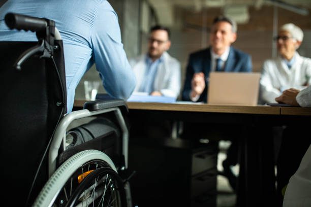 Close up of unrecognizable businessman in a wheelchair on a meeting in the office.