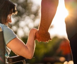 Close up women on a wheel chair holding mens hand